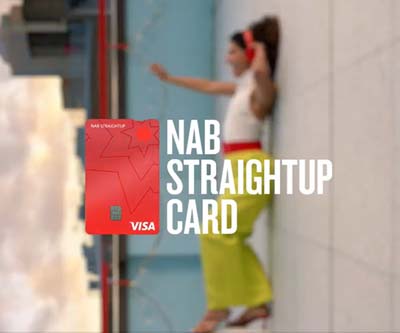 Red NAB StraightUp Credit Card displayed over a blurred person in background